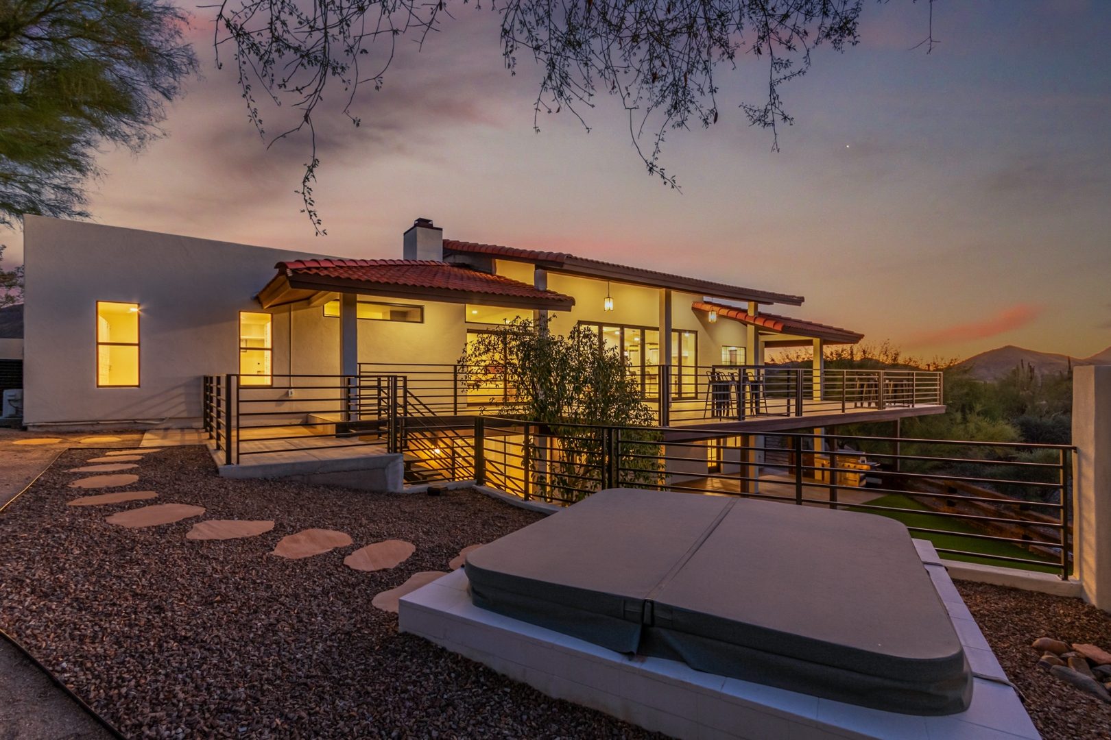 Twilight photograph of a modern Arizona desert home with pool and warm interior lighting